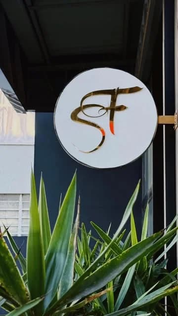 Fachada do Studio F com o monograma dourado e vegetação